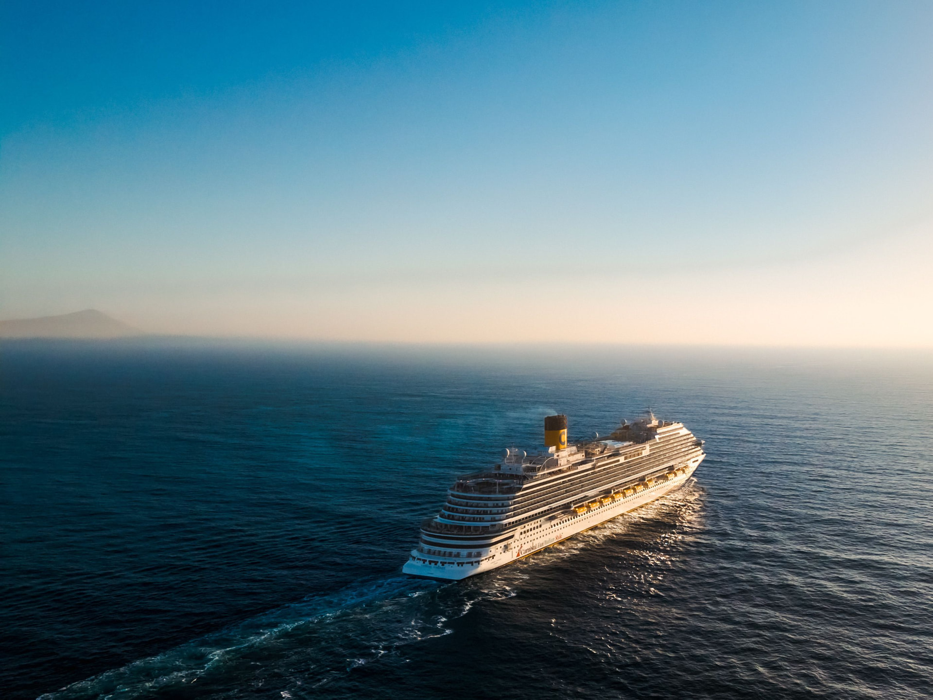 A cruise ship sailing on calm open water at sunset